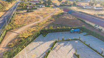 Vista aérea de un estacionamiento con una camioneta azul, rodeado de vegetación y edificios residenciales.