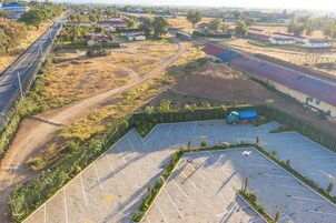 Vista aérea de un estacionamiento con una camioneta azul, rodeado de vegetación y edificios residenciales.