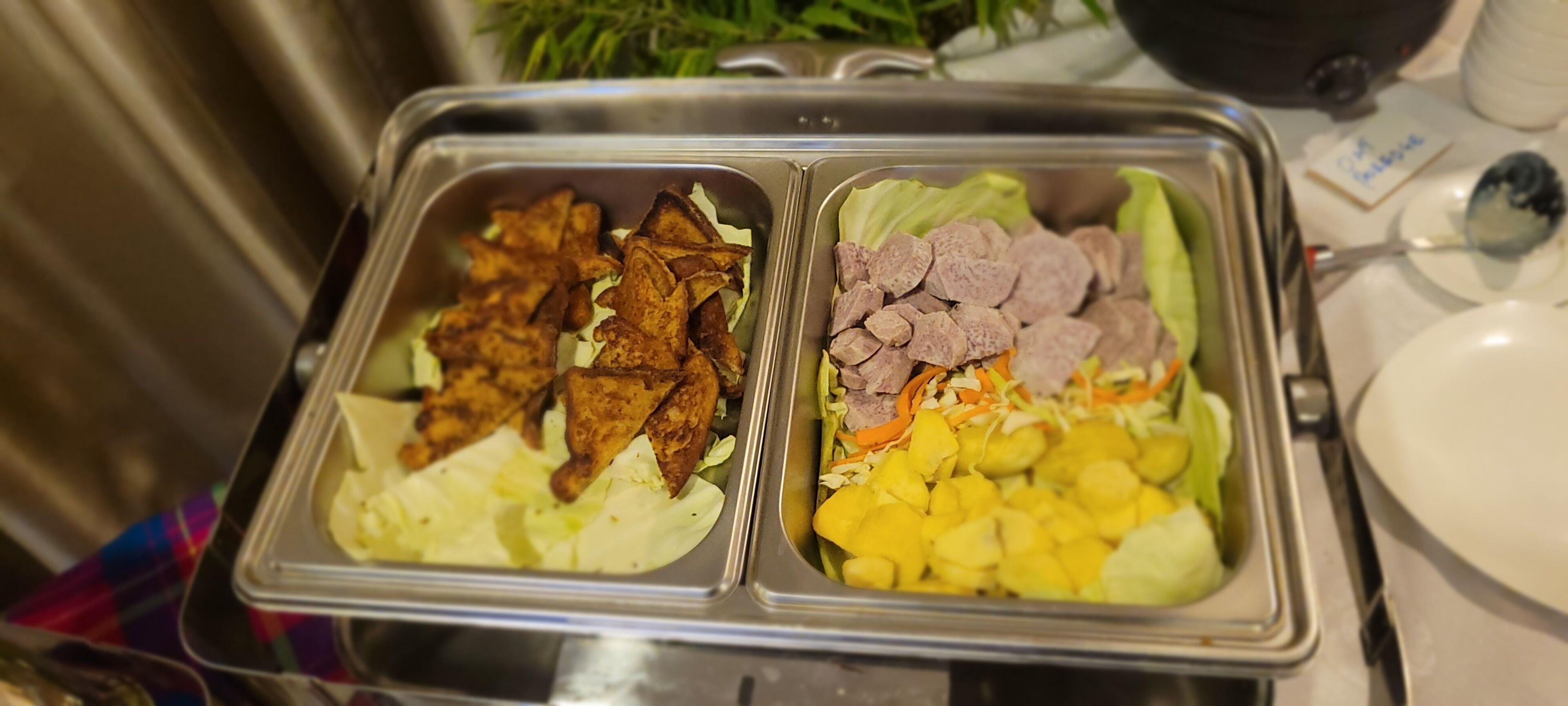 Un bufé con dos secciones: una con pollo frito y otra con carnes y verduras cortadas.