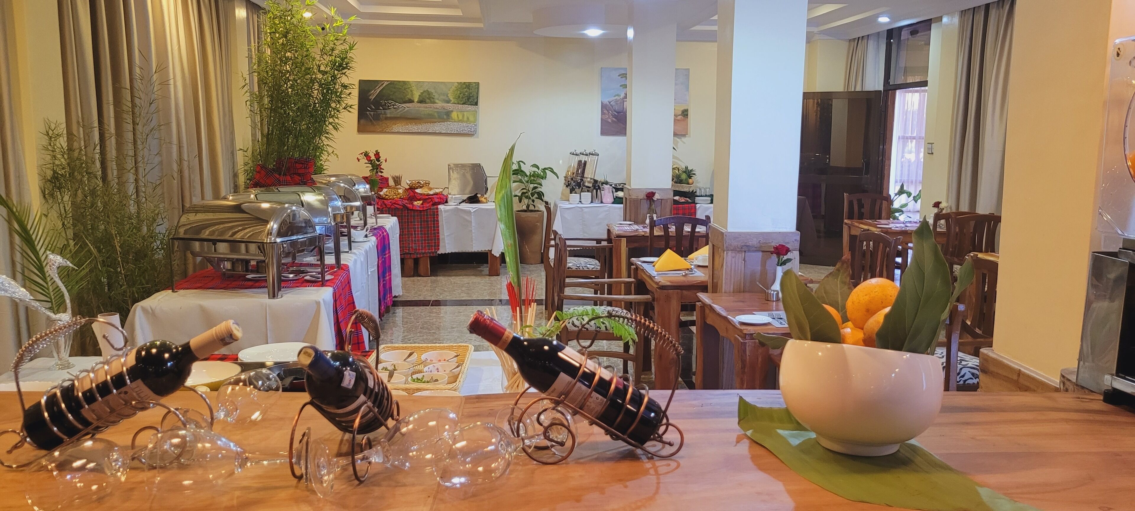 A dining area with tables set for meals, surrounded by potted plants and artwork.