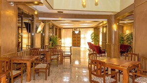 Un hall amplio con muebles de madera, un candelabro central y ventanas grandes.