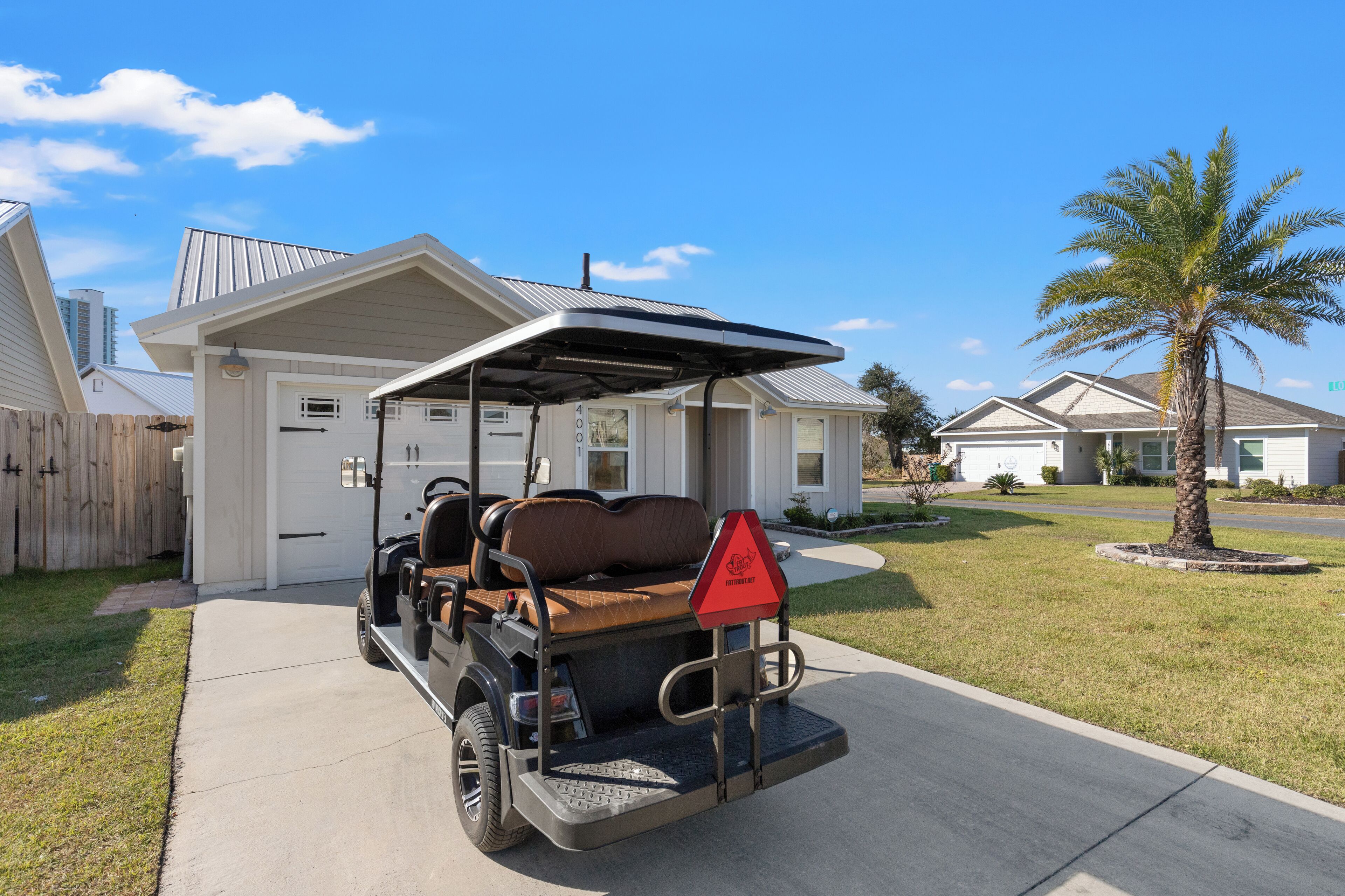 A residential house with a covered porch, a golf cart, and a palm tree.