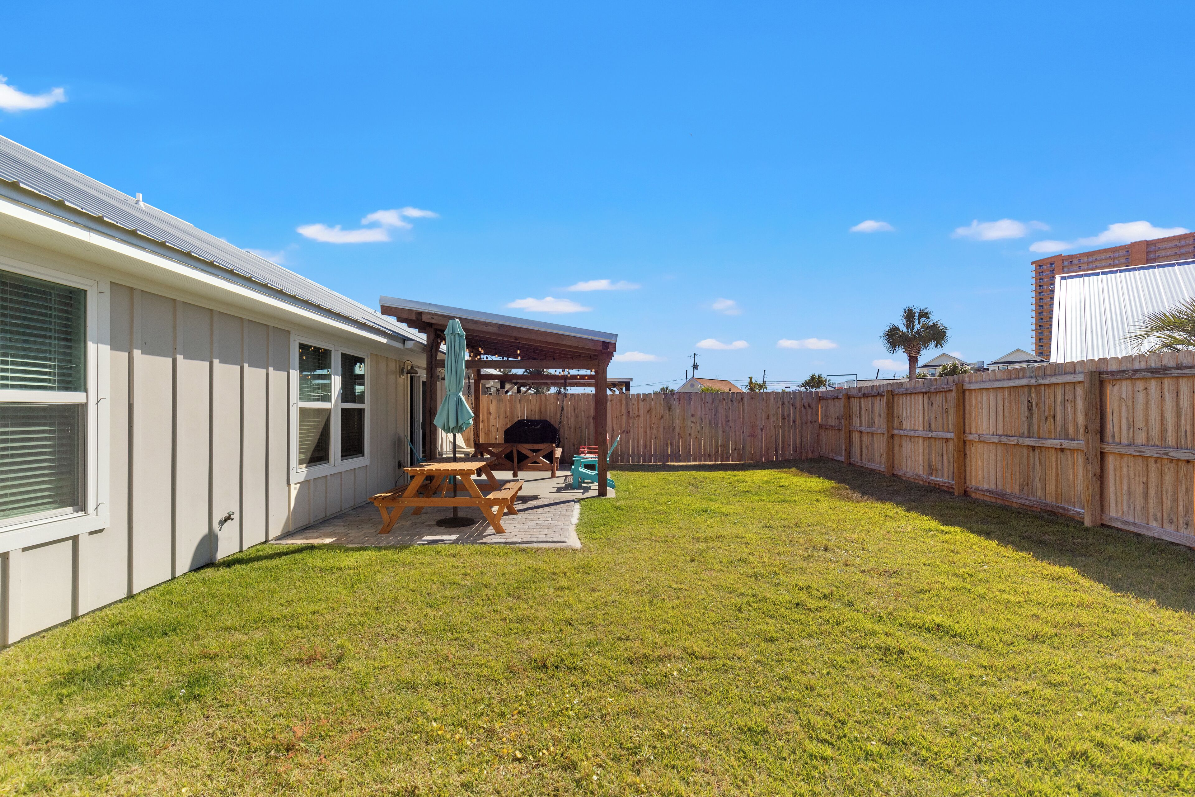 A backyard with a covered patio, a barbecue grill, and a picnic table.
