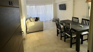 A spacious living area with a sofa, dining table, and chairs. There is a TV mounted on the wall and an air conditioning unit. - Apartment in the center with a beautiful view of the city (mendoza)