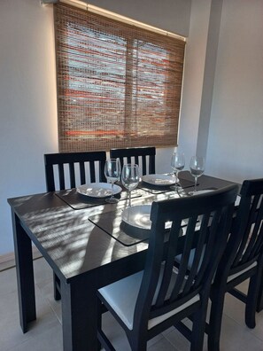 A dining table with chairs, plates, and wine glasses set for four. - Apartment in the center with a beautiful view of the city (mendoza)