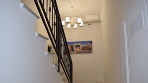 A staircase with a black railing, a chandelier, and a framed picture on the wall. - Residenza Aurea (Offida)