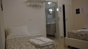 A bedroom with a bed, a bedside table, and a bathroom visible through an open door. - Residenza Aurea (Offida)