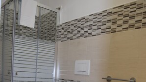 A bathroom with a glass shower enclosure, a toilet, a bidet, and a sink. - Residenza Aurea (Offida)