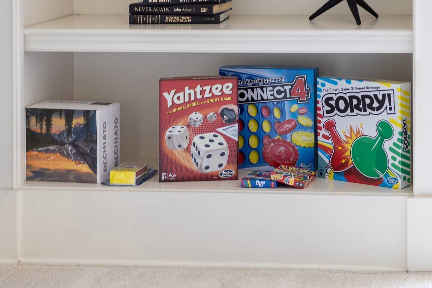A shelf with various board games including Yahtzee, Connect 4, and Sorry!.