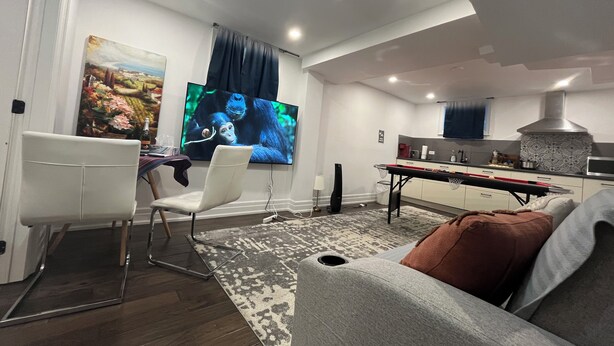 Una sala moderna con una televisión de pantalla plana, una mesa de comedor y un sofá.