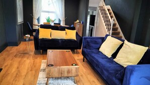 Un salon moderne avec un canapé bleu foncé, une table basse en bois et un divan bleu.