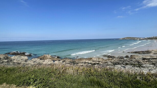 Un paysage côtier caractérisé par une rive rocheuse, un ciel bleu clair et une mer calme.