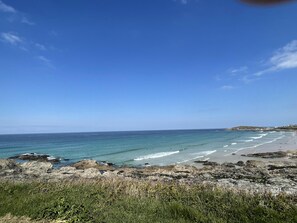 A coastal landscape with a rocky shoreline, clear blue sky, and calm sea. - Impeccable 3-bed House in Newquay (Newquay)