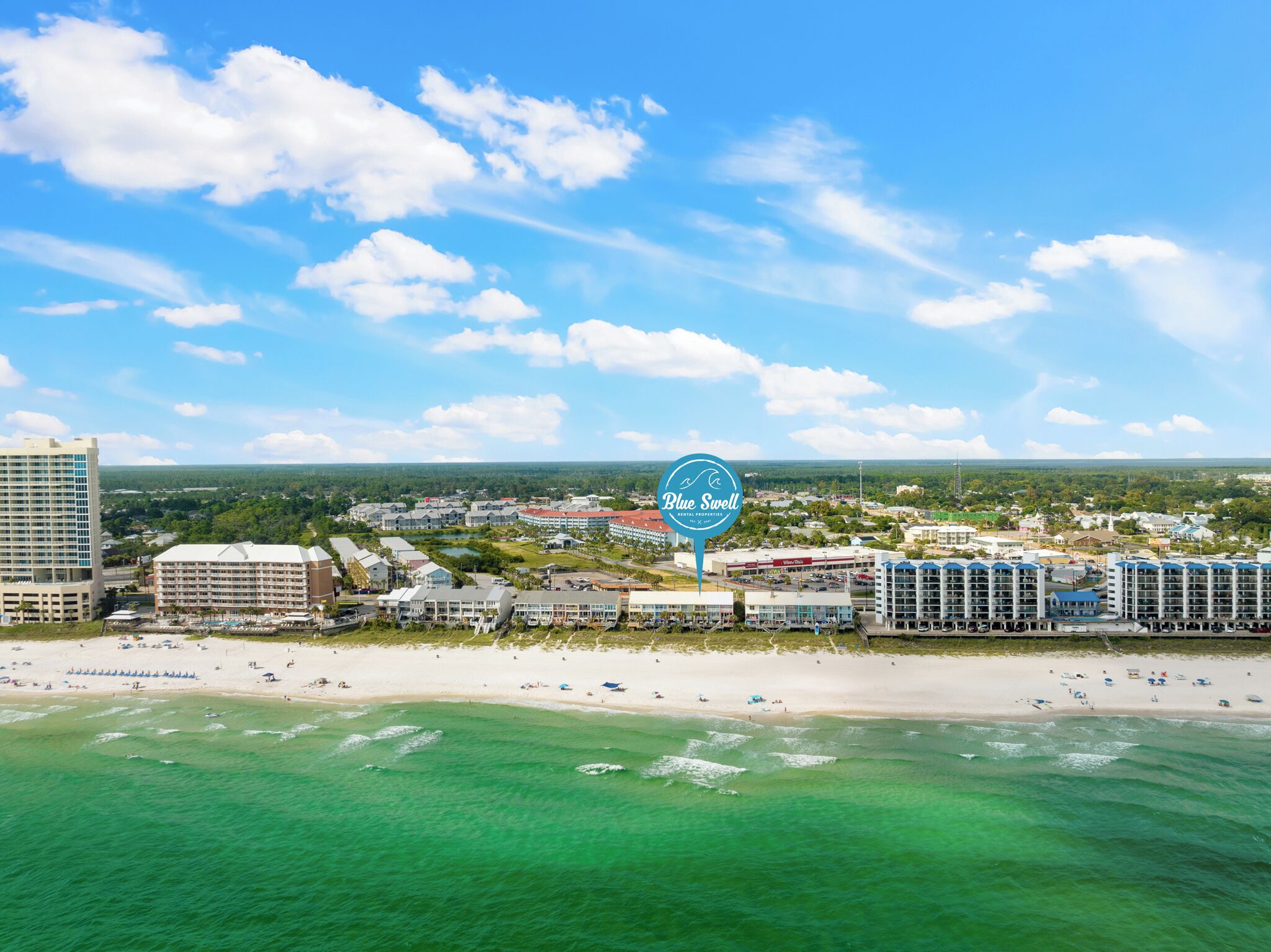 A coastal hotel area with beachfront properties, a sandy beach, and a clear blue sky.
