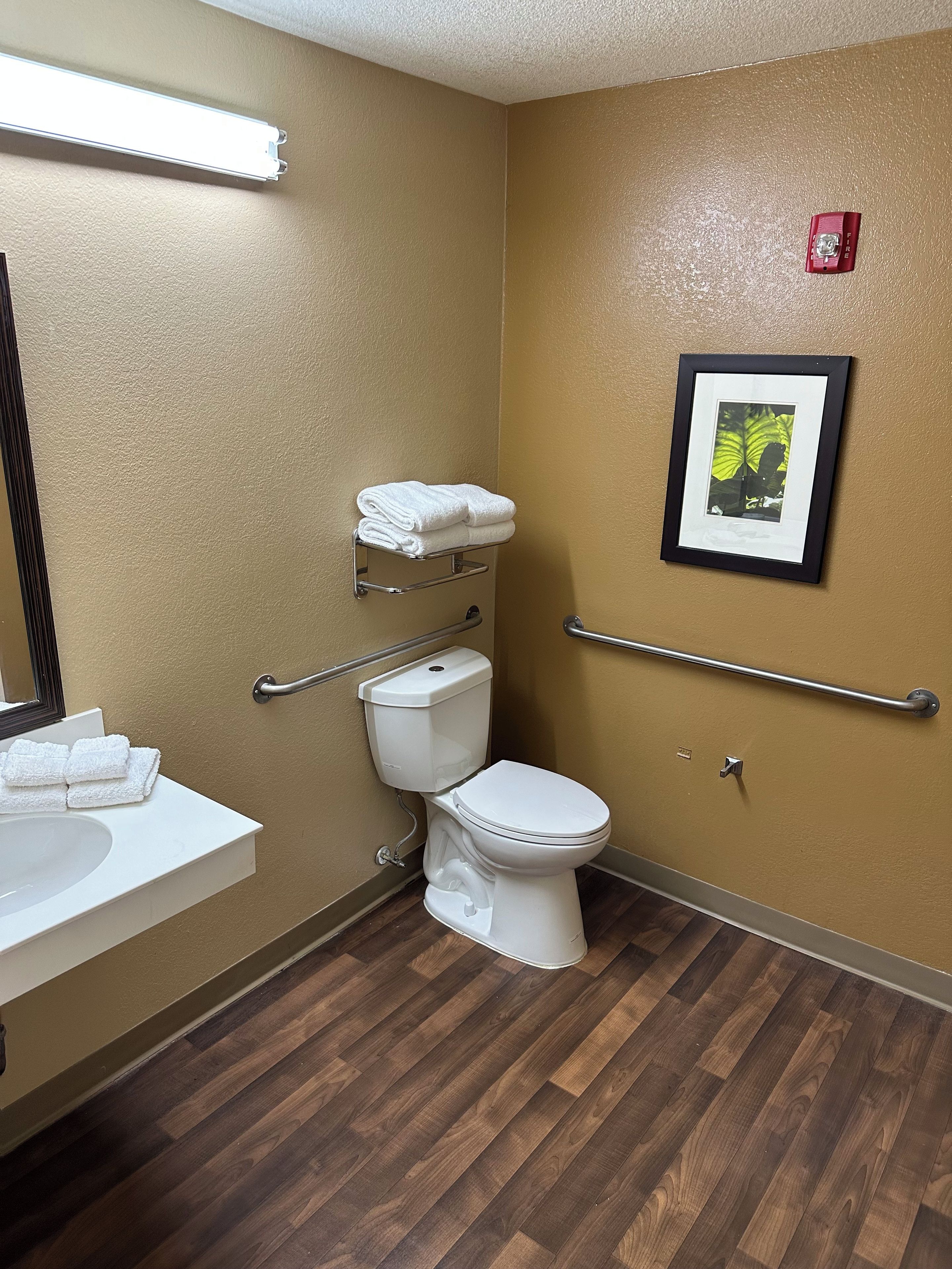 A bathroom with a white sink, toilet, and a framed picture on the wall.