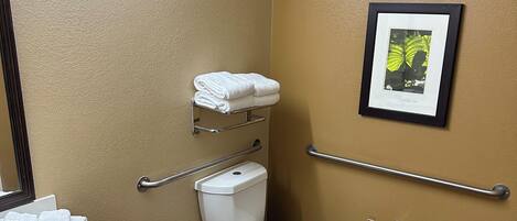 A bathroom with a white sink, toilet, and a framed picture on the wall.