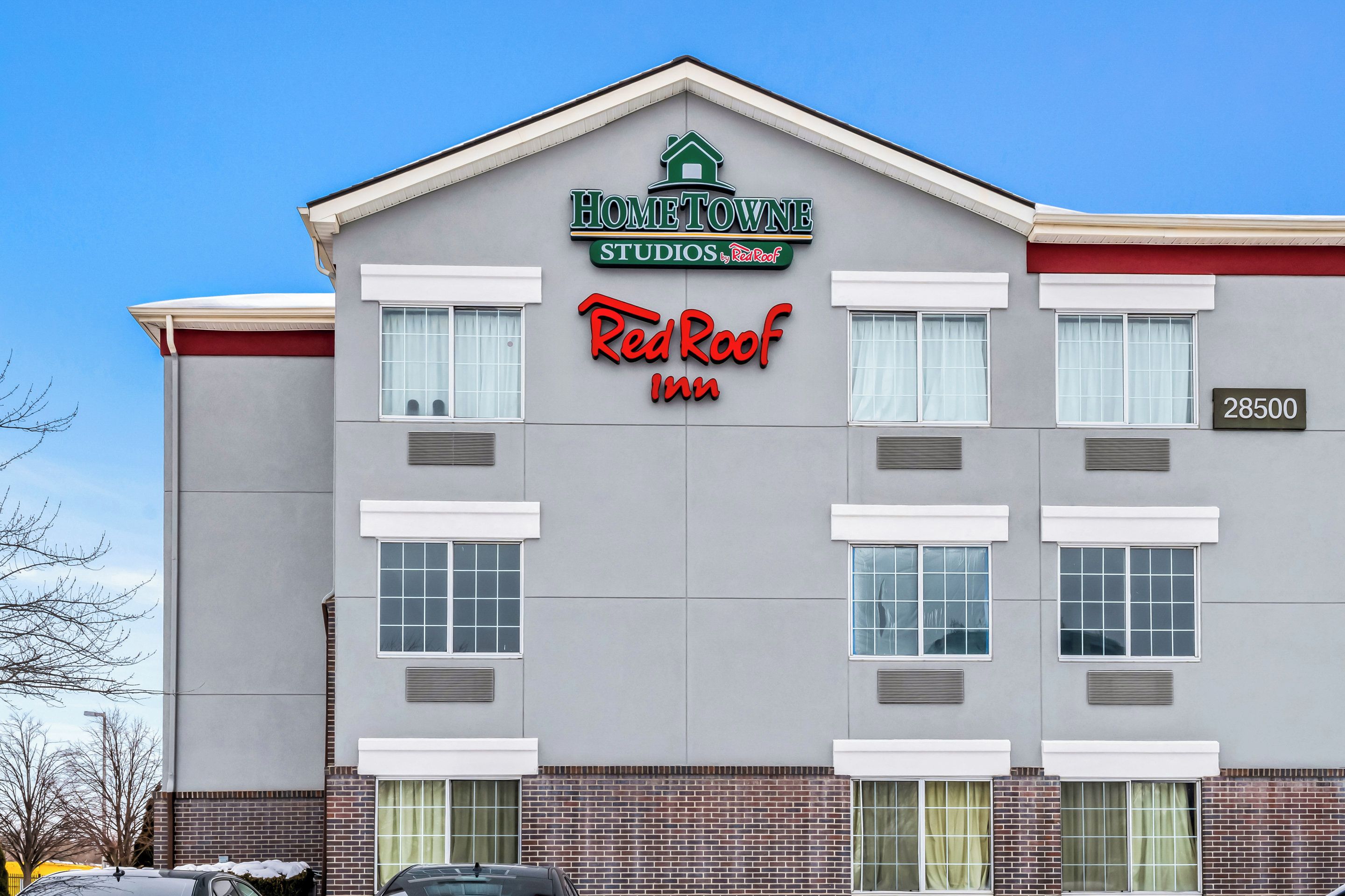 Un edificio con un letrero que dice "HOMETOWNE STUDIOS Red Roof Inn" y la dirección "28500".