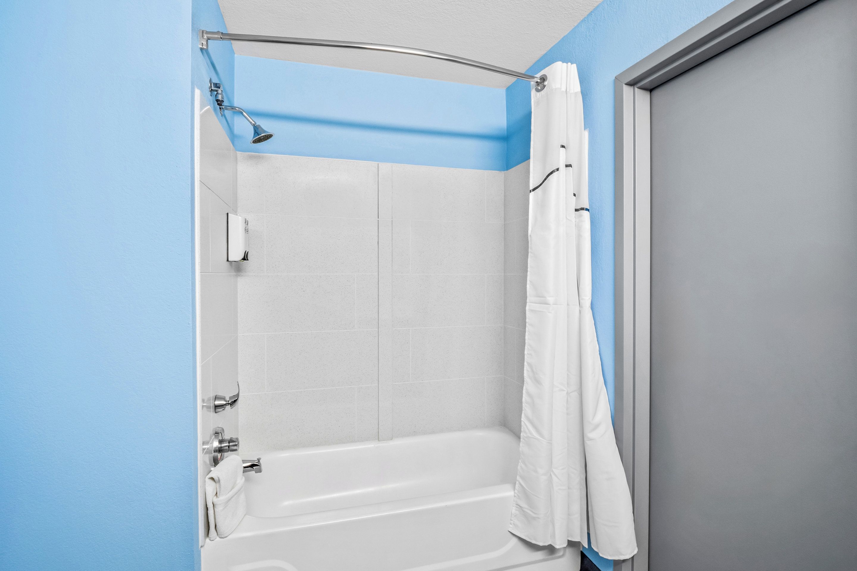 A bathroom with a bathtub, shower, and a door.