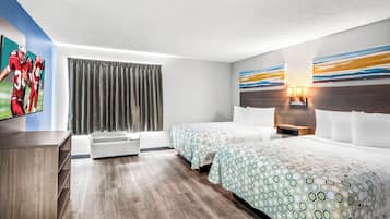A hotel room with two beds, a TV, a large window with curtains, and a wall with a geometric pattern.