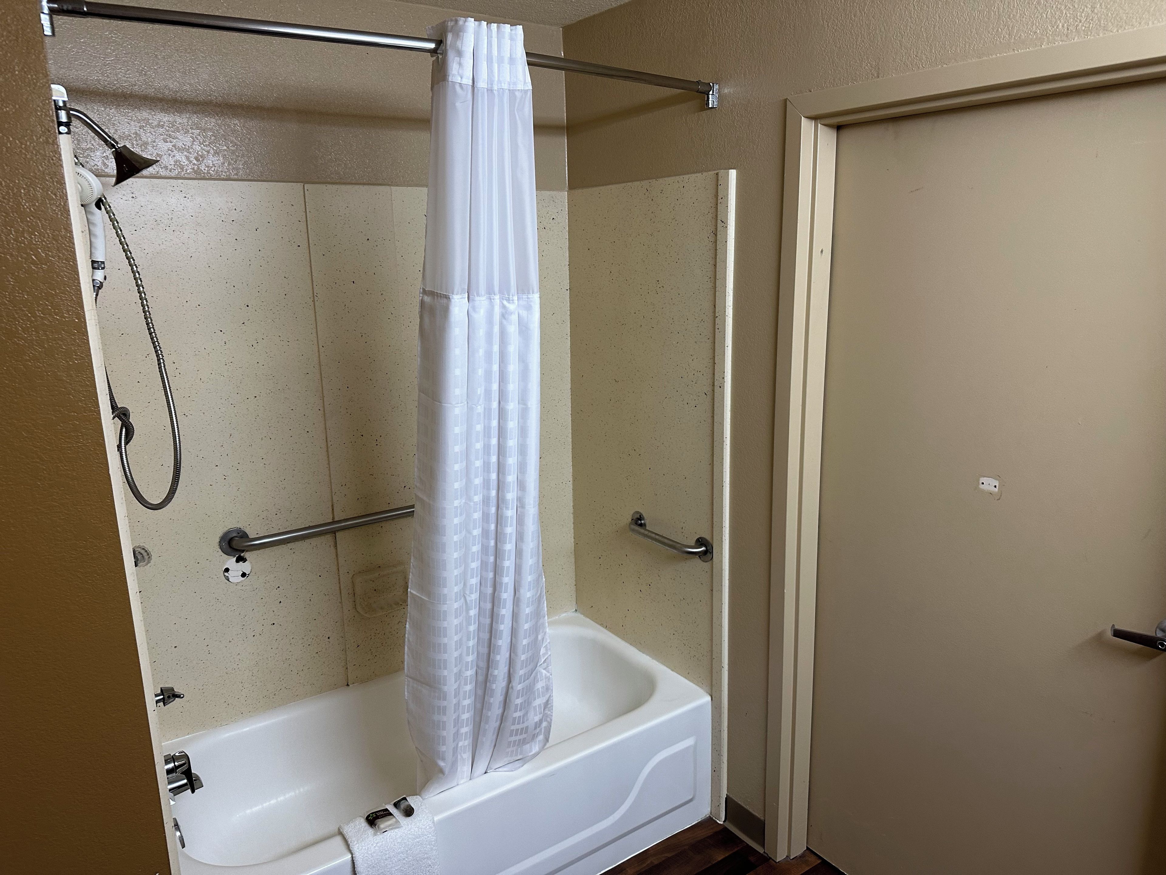 Un baño con bañera, ducha y una puerta.