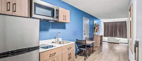 A modern kitchen with wooden cabinets, a stainless steel refrigerator, a microwave, and a sink.