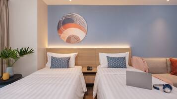 Habitación de hotel con dos camas, una laptop, audífonos y una obra de arte en la pared.