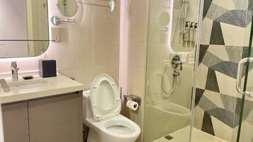 Un baño moderno con inodoro, lavamanos, espejo y ducha.
