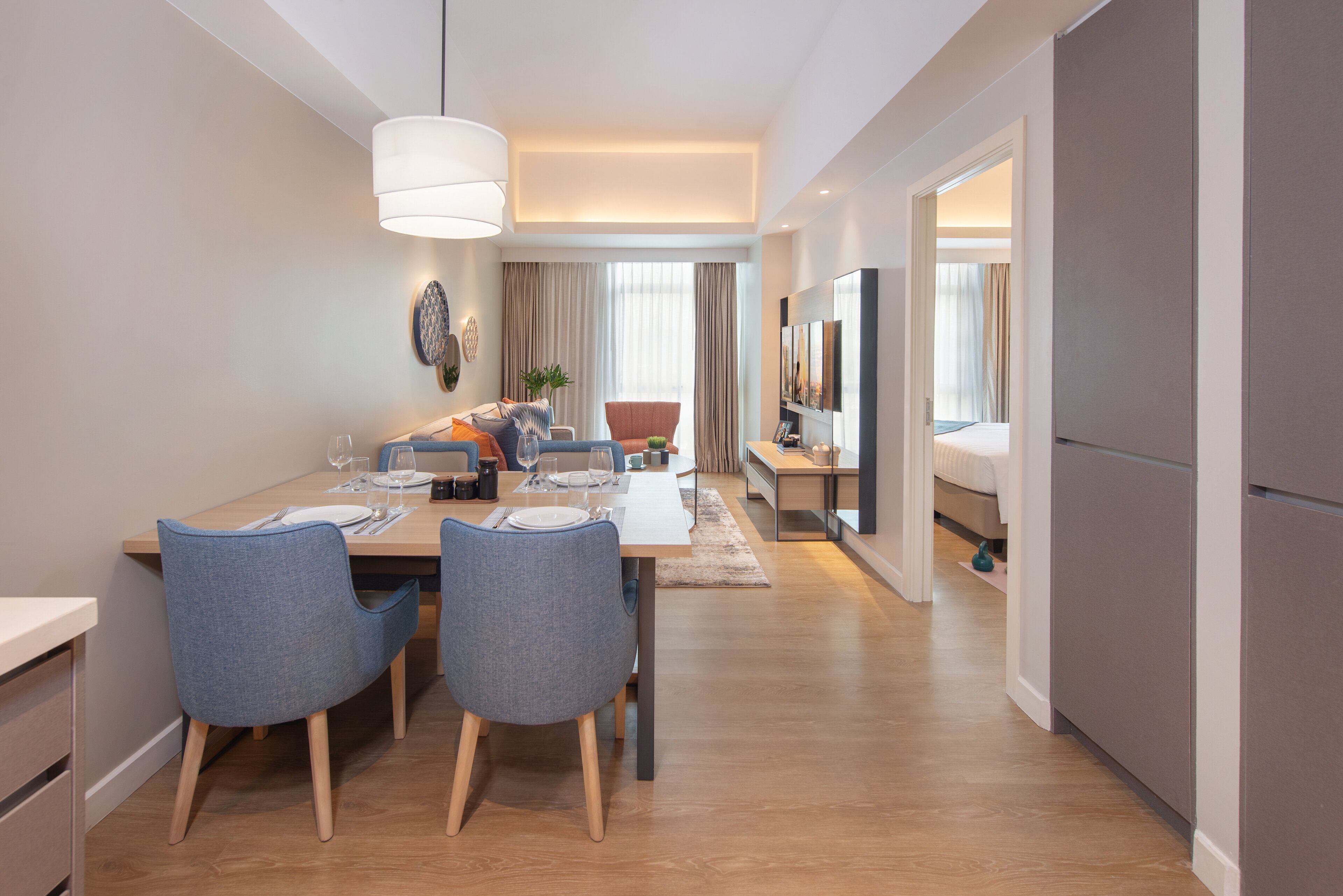 Habitación de hotel moderna con zona de comedor, cama y televisor.