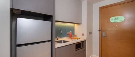 A compact kitchen with a refrigerator, sink, and microwave.
