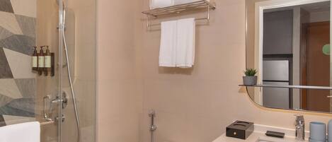 A modern bathroom with a glass-enclosed shower, a toilet, a sink, and a mirror.