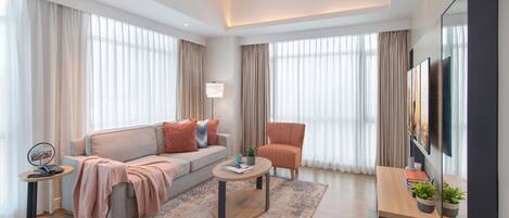 Una sala de estar moderna con un sofá, un sillón, una mesa de centro y un televisor.