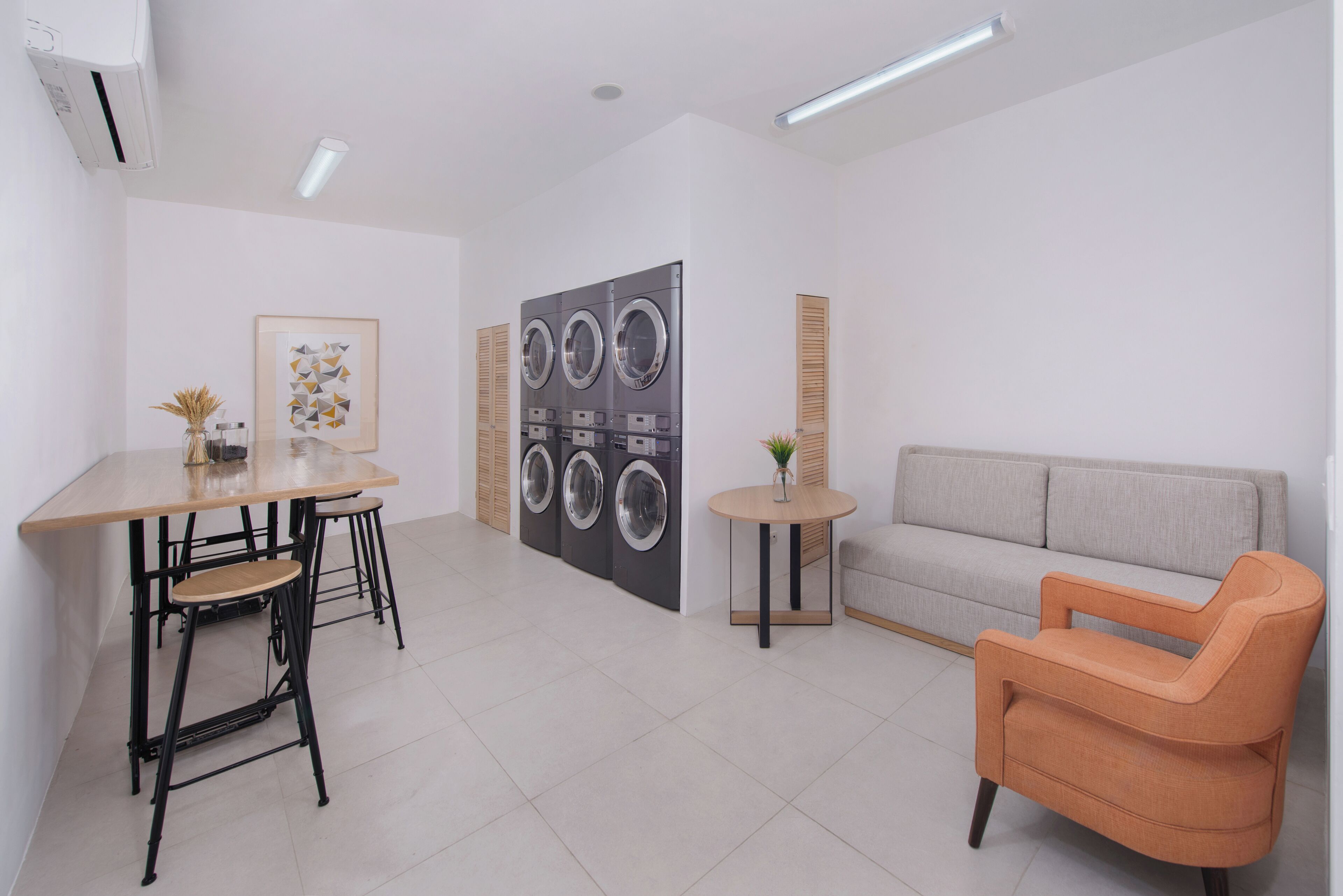 Una habitación moderna con una mesa de comedor, sillas, un sofá, una mesita redonda y un lavadero empotrado en la pared.