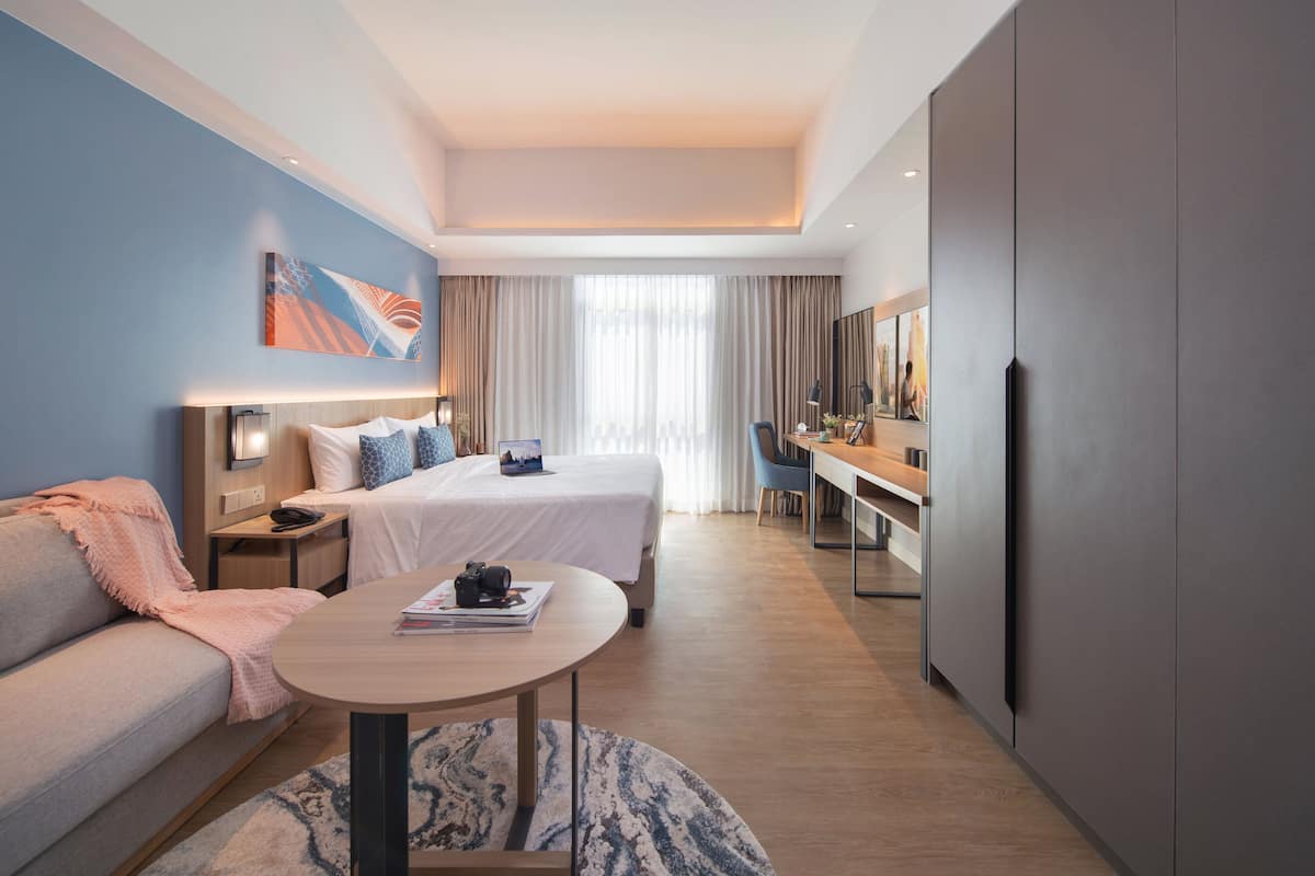 A modern hotel room with a bed, a sofa, a desk, and a television.