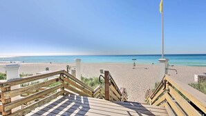 Una escalera de madera que lleva a una playa con vista despejada al océano.