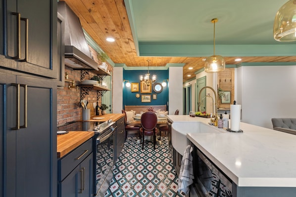 A kitchen with a wooden ceiling, a dining area with a table and chairs, and a large island with a white countertop.