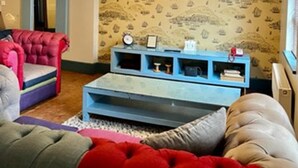 A living room with a large flat-screen TV mounted on the wall, a blue entertainment unit, and a red and grey sofa. - Chester Centre 2-bed Apartment -by Oddfellows (Chester)