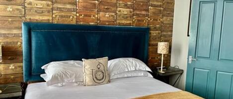 A bed with a blue headboard, white bedding, and a beige throw blanket.