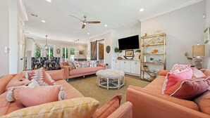 A spacious living room with a large sofa, ottoman, and a dining area in the background.