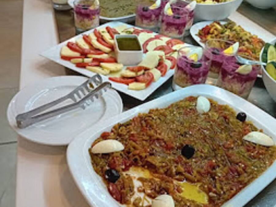A buffet table with various dishes, including a large platter of rice with vegetables and eggs, and several smaller dishes with different salads and appetizers.