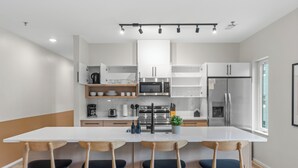 Een moderne keuken met witte kasten, een centraal eiland met barkrukken, roestvrijstalen apparatuur en een raam voor natuurlijk licht.