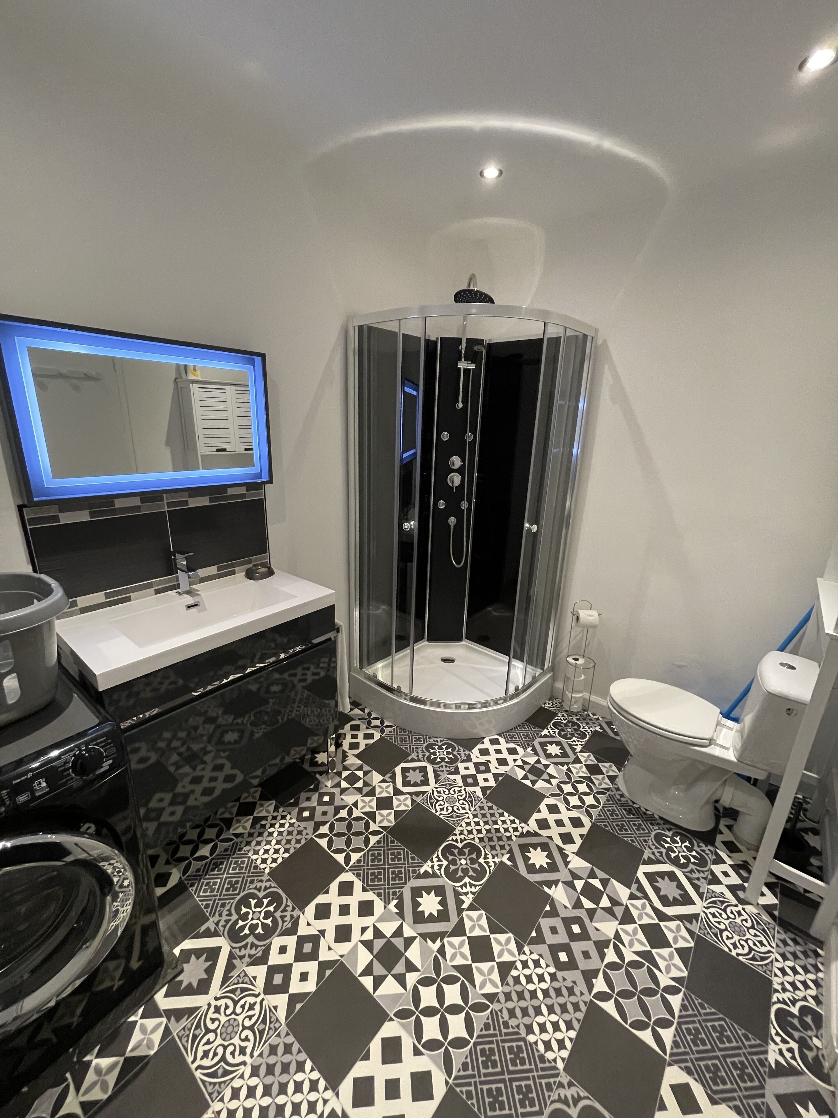 A modern bathroom with a glass-enclosed shower, a sink with a mirror, and a toilet.