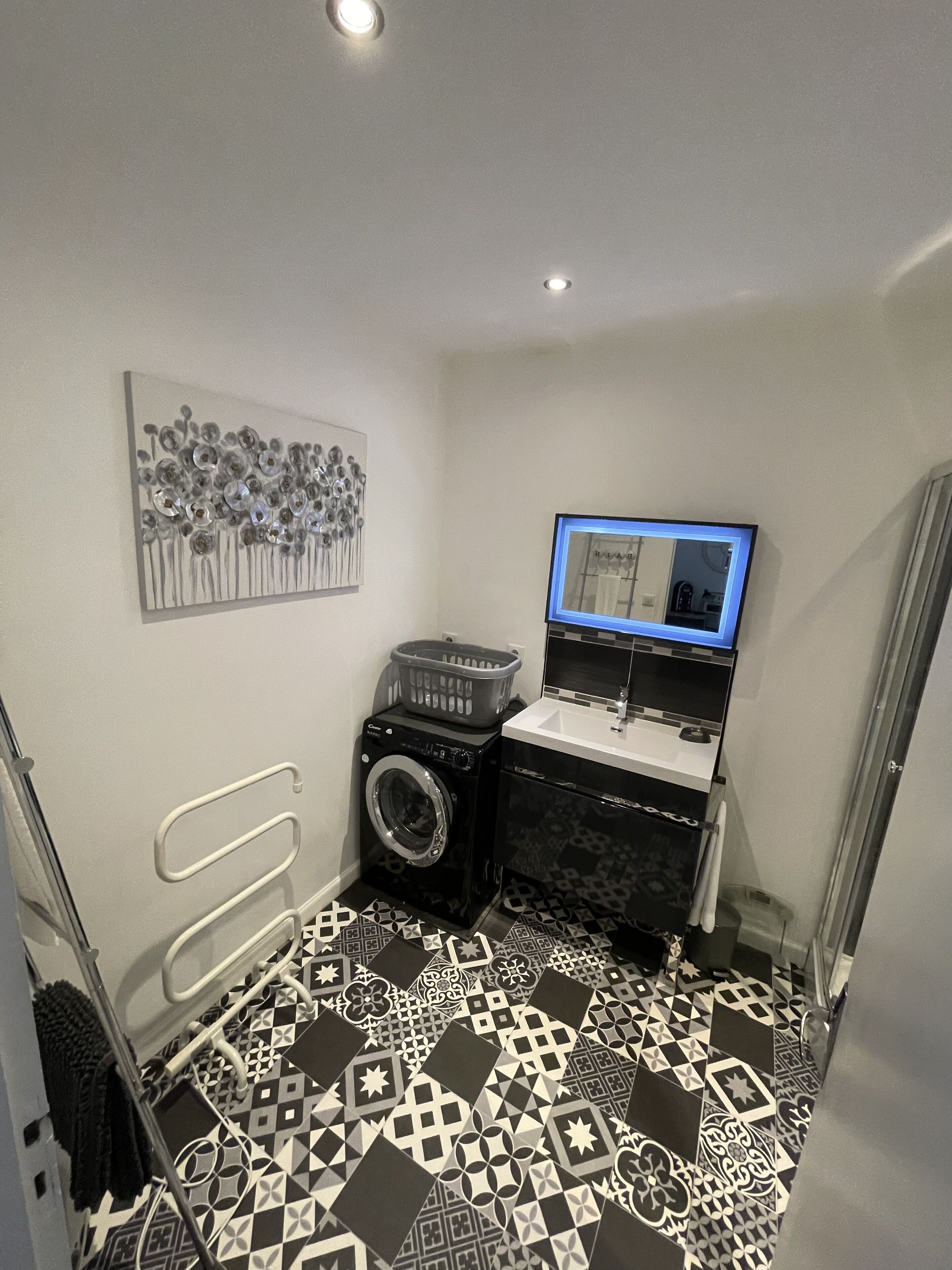 Een kleine wasruimte met een wasmachine, een droger, een wasbak en een spiegel.