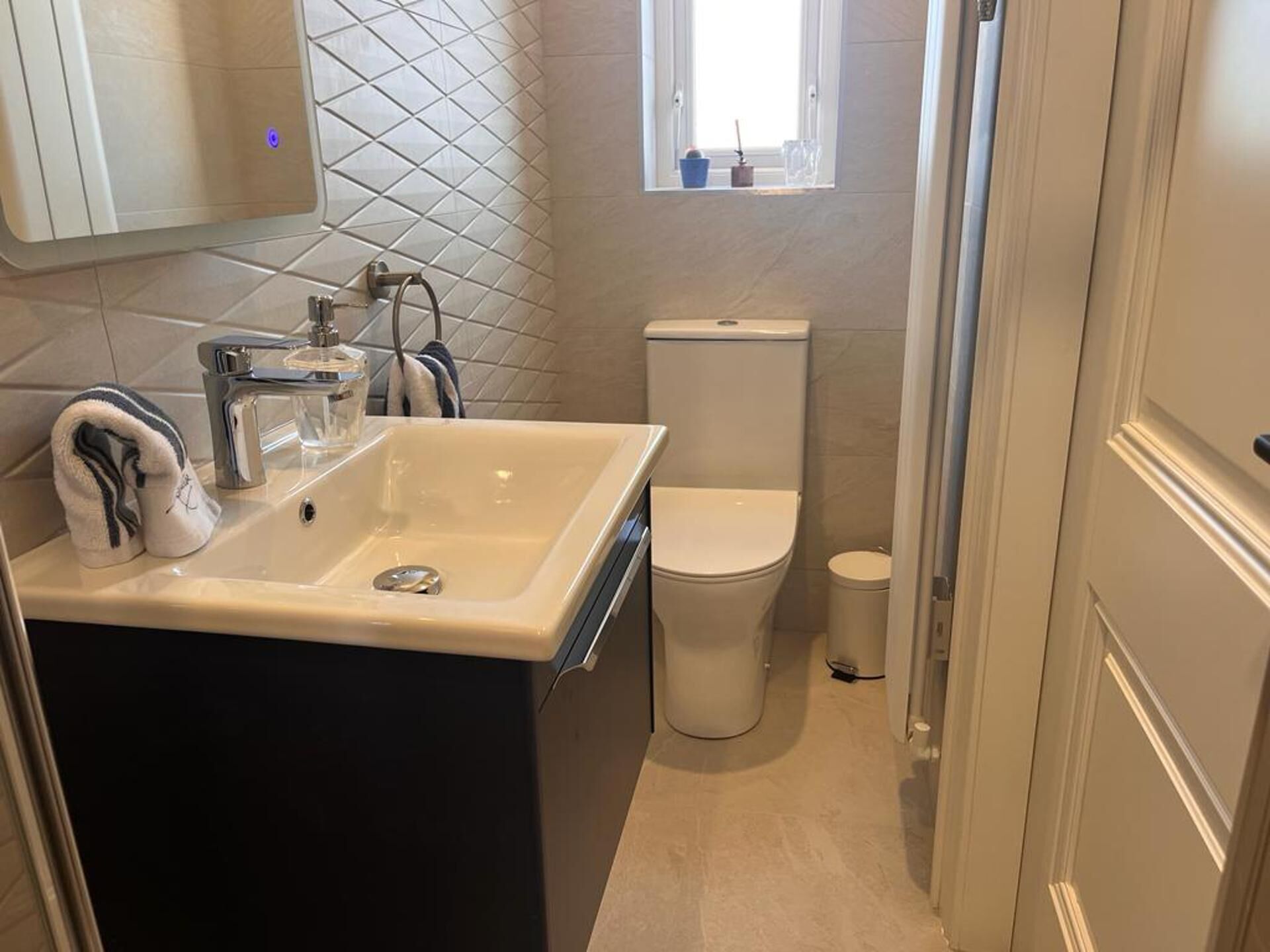 A bathroom with a sink, toilet, and a window.