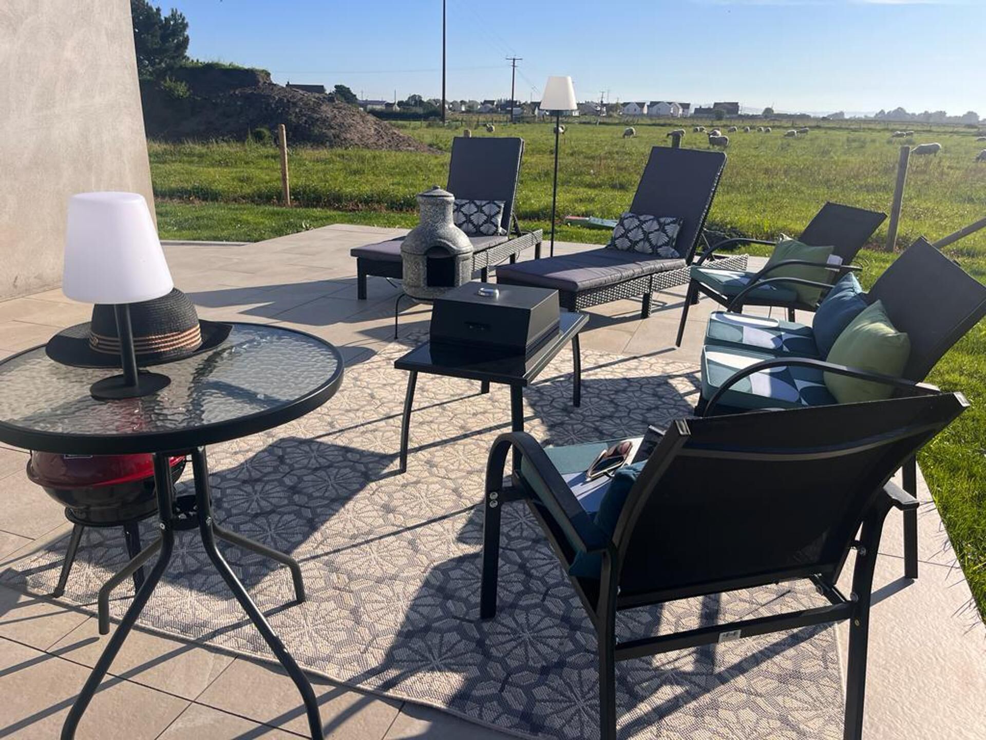 An outdoor patio with lounge chairs, a table, and a fireplace.
