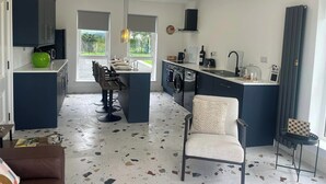 A compact kitchen with a central island, a washing machine, and a dining area with a chair and table.