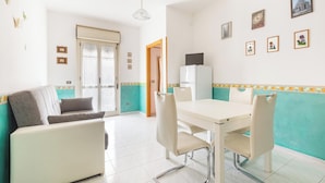 Una habitación con una mesa de comedor, sillas, un sofá y una televisión.
