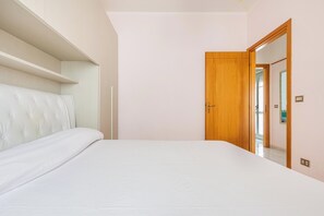 Une chambre à coucher avec un lit, une porte en bois et un mur blanc.