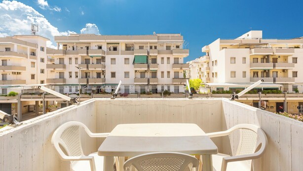 Una terraza con una mesa y sillas, con vista a una hilera de edificios residenciales.