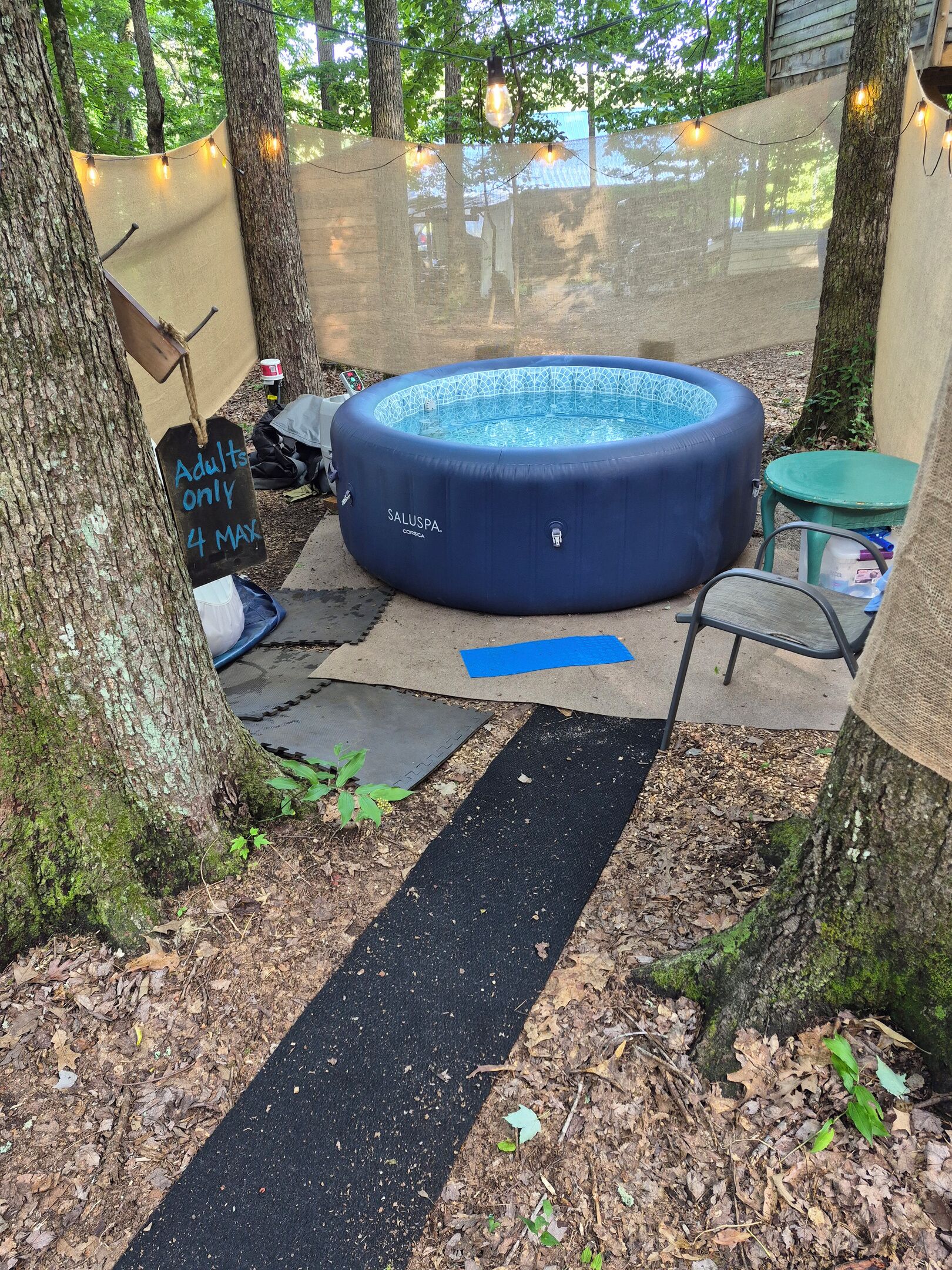 Un jacuzzi gonflable, avec une pancarte indiquant « Réservé aux adultes, maximum 4 personnes », installé dans un jardin.