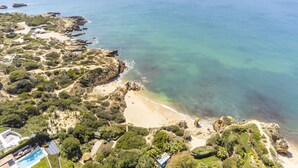An aerial view of a coastal property with a beach, rocky shoreline, and lush vegetation. - Spacious villa with BBQ and pool in Albufeira (Albufeira)